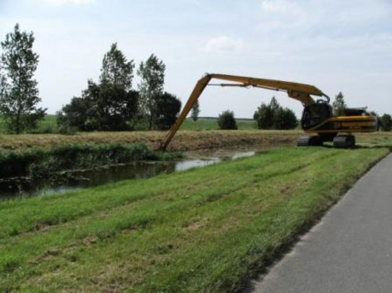 A tracked excavator uses its long-reach hydraulic arm to carry out routine weed cutting and flailing of the drain’s bank sides