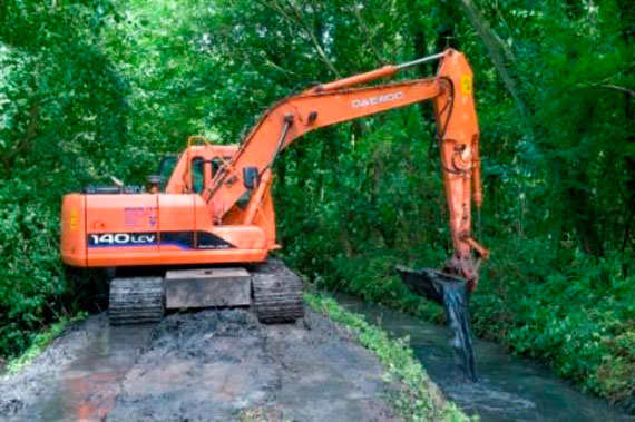 A tracked excavator uses its hydraulic arm to carry out dredging of the River Mermaid, a sight no longer seen on this stretch of water - now the focus has moved to improve habitats for plants, invertebrates and fish
